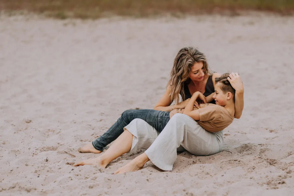 moeder met zoon knuffelen op het strand